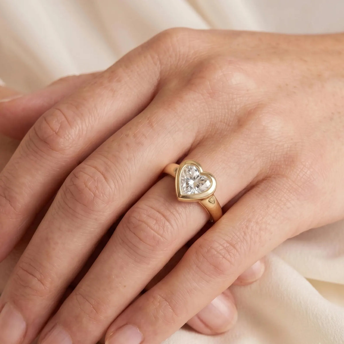 lifestyle-hand-view-of-heart-cut-lab-diamond-bezel-set-ring