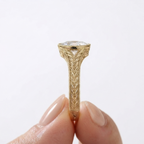 Hand holding a vintage-style yellow gold engagement ring featuring a 2 CT oval lab-grown diamond.
