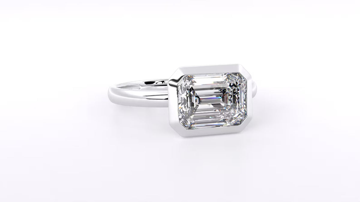 Side profile view of a 3 CT emerald cut lab-grown diamond engagement ring in a bezel setting.