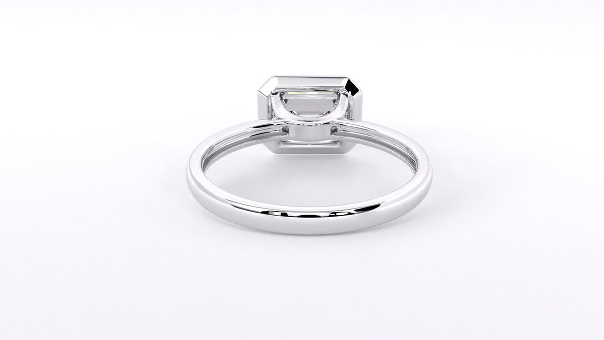 A silver-toned ring with a rectangular emerald-cut clear gemstone in a four-prong setting, shown on a plain white background.
