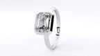 Under-gallery and profile view of a sleek white gold ring featuring a bezel-set emerald cut diamond.