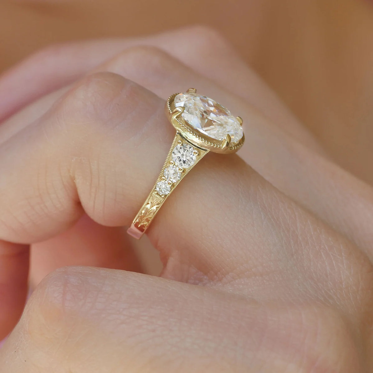 Side profile view of a 4 CT oval lab-grown diamond vintage ring worn on a hand, showing leaf engravings.