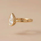 Side profile of a 3 carat pear lab diamond ring showcasing the elevated bezel basket and polished yellow gold shank.