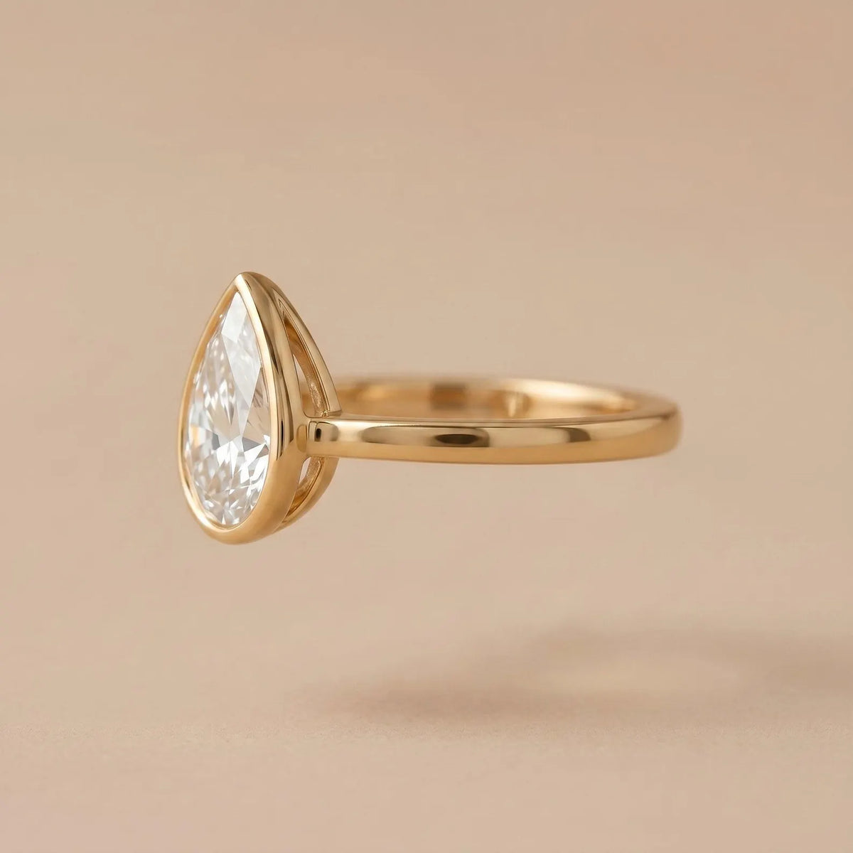 Side profile of a 3 carat pear lab diamond ring showcasing the elevated bezel basket and polished yellow gold shank.