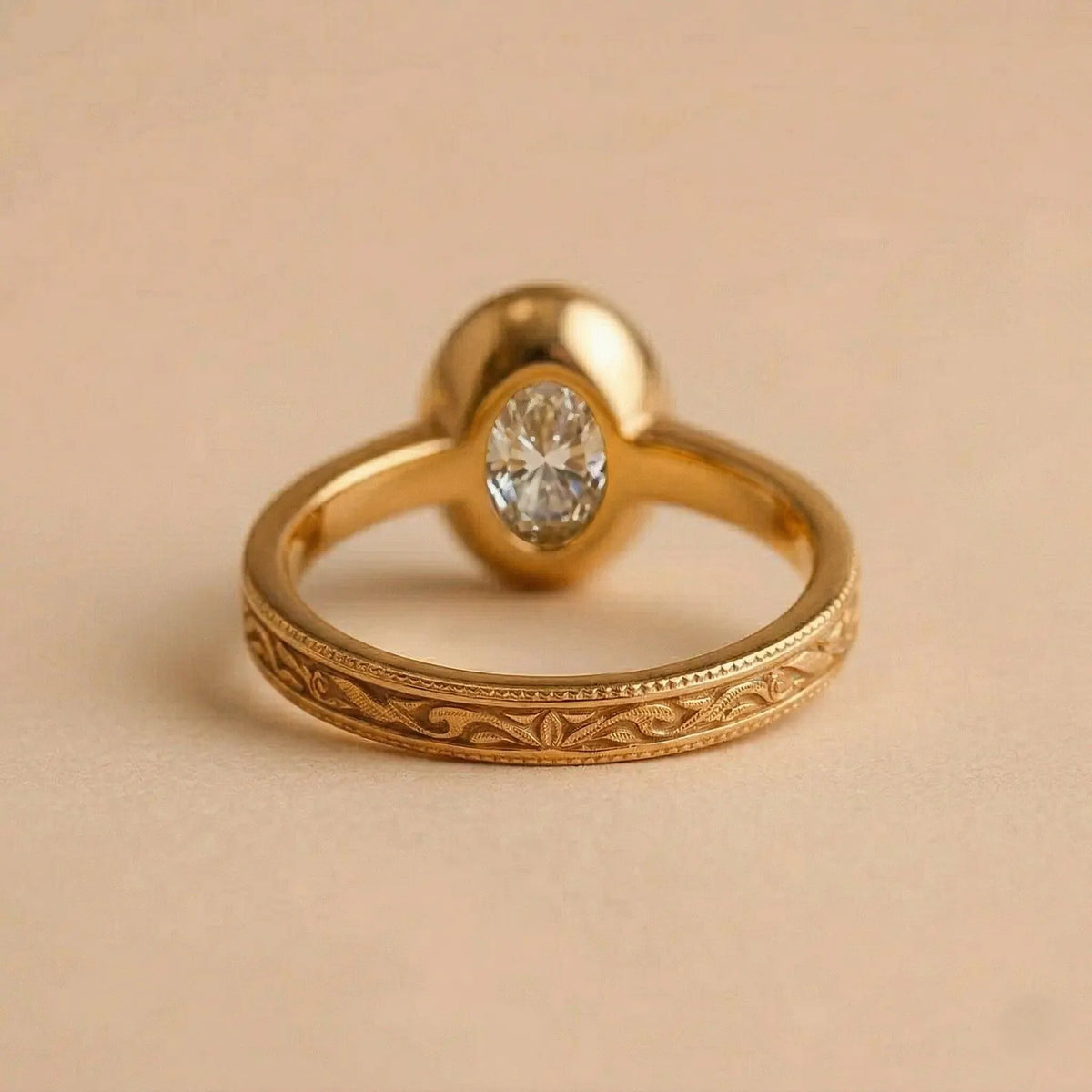 Underside view of a 2 carat oval diamond ring showing the solid gold bezel setting and floral carved shank.