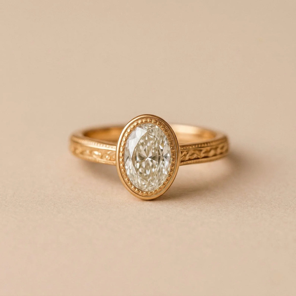 Front view of a 2 CT oval lab diamond framed in a milgrain yellow gold bezel setting.