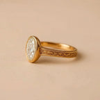 Profile perspective highlighting the hand-carved floral scrollwork on the yellow gold band of an oval bezel ring.