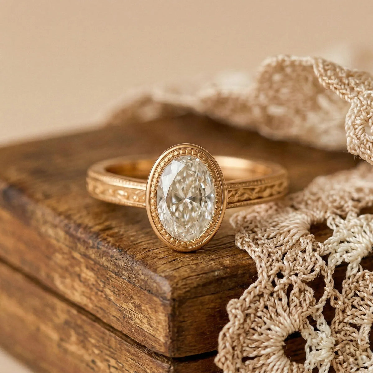 Antique style 2 carat oval lab diamond engagement ring resting on a wooden box with crocheted lace background.