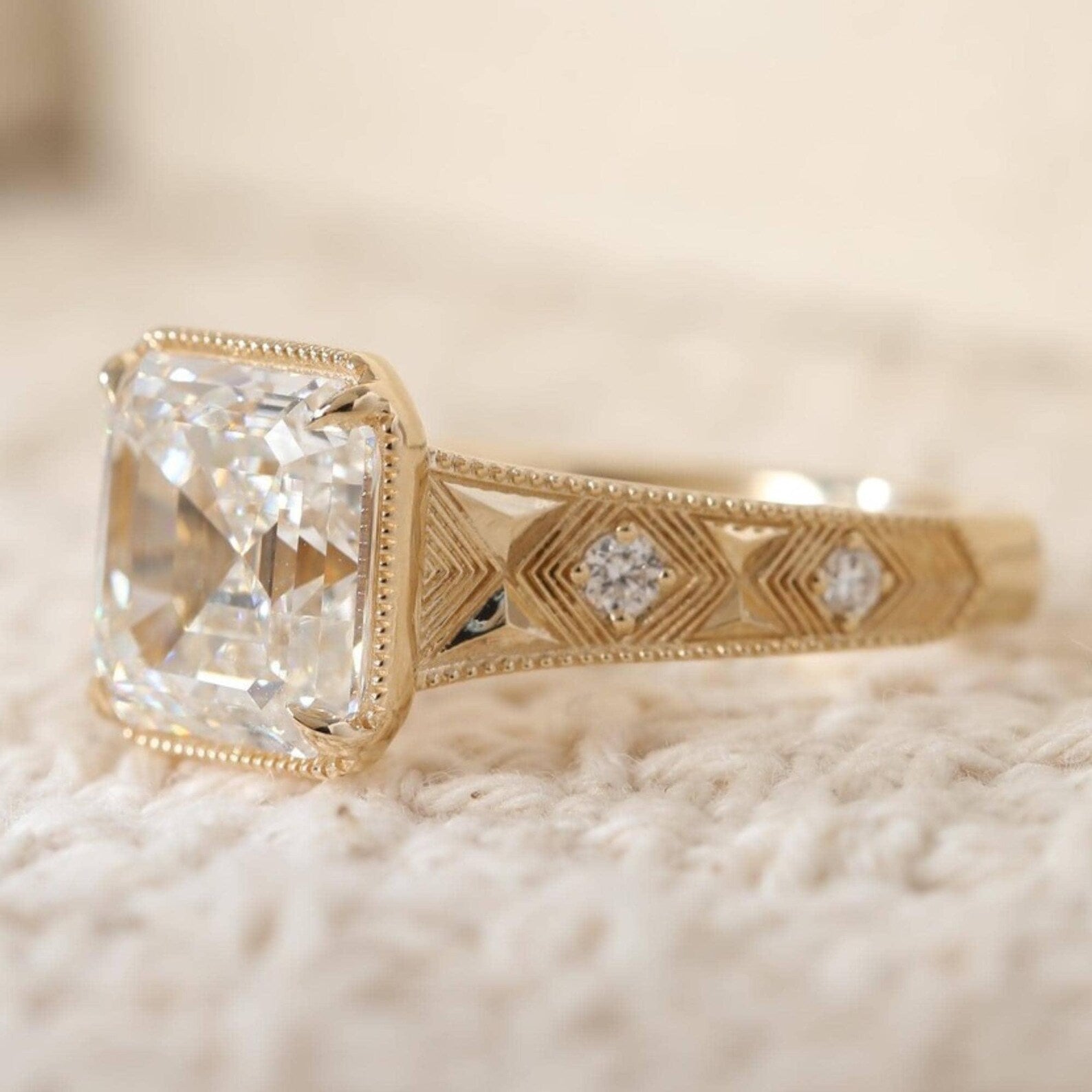 Side view of a 3 carat Asscher cut lab diamond ring highlighting the hand-engraved chevron pattern band set with bezel round accent diamonds.