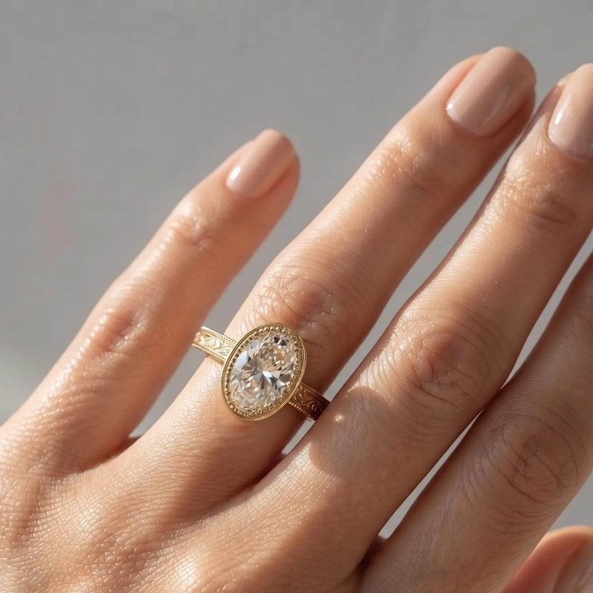 Person wearing a 3 CT oval lab diamond engagement ring with a vintage yellow gold engraved band.