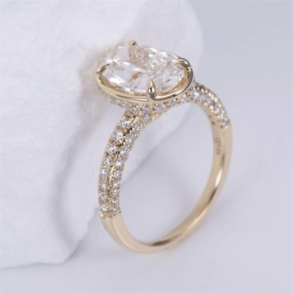 Side angle of a 3 CT oval lab-grown diamond engagement ring in 14K yellow gold with a micro-pavé band and hidden halo.
