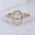 Front top view of a 3 CT oval lab-grown diamond ring with thin bezel frame, corner prongs, and diamond pavé shank.