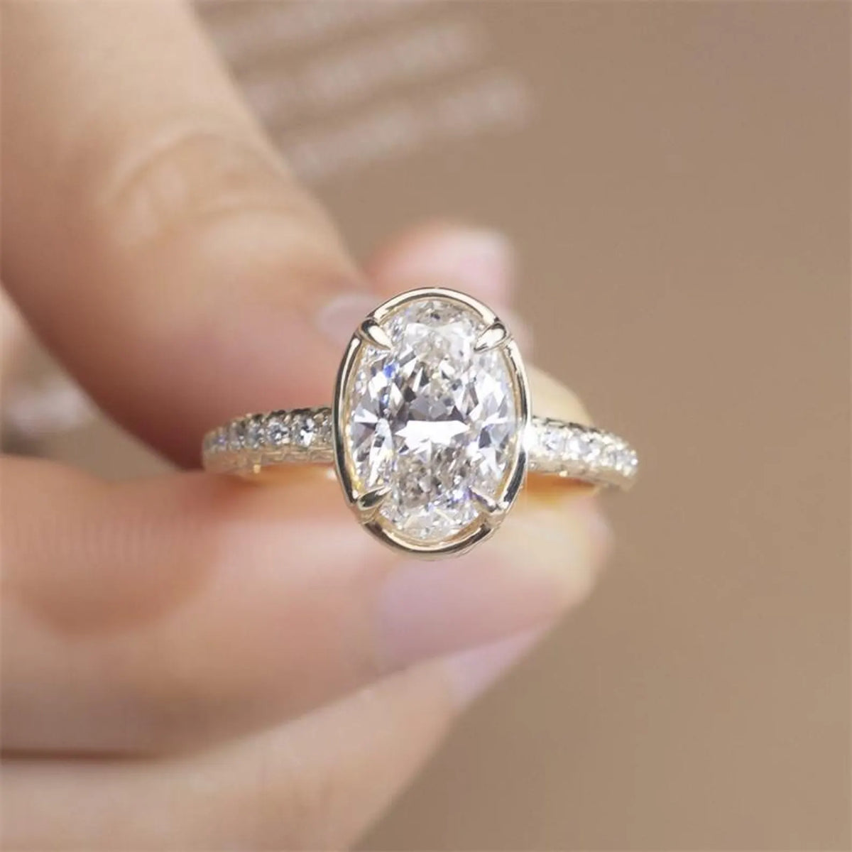 Close-up front view of a 3 CT oval lab-grown diamond ring held in hand showcasing stone brilliance and yellow gold setting.