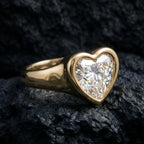 3 CT heart lab-grown diamond ring in a smooth yellow gold full bezel signet setting, angled view on dark rock background.