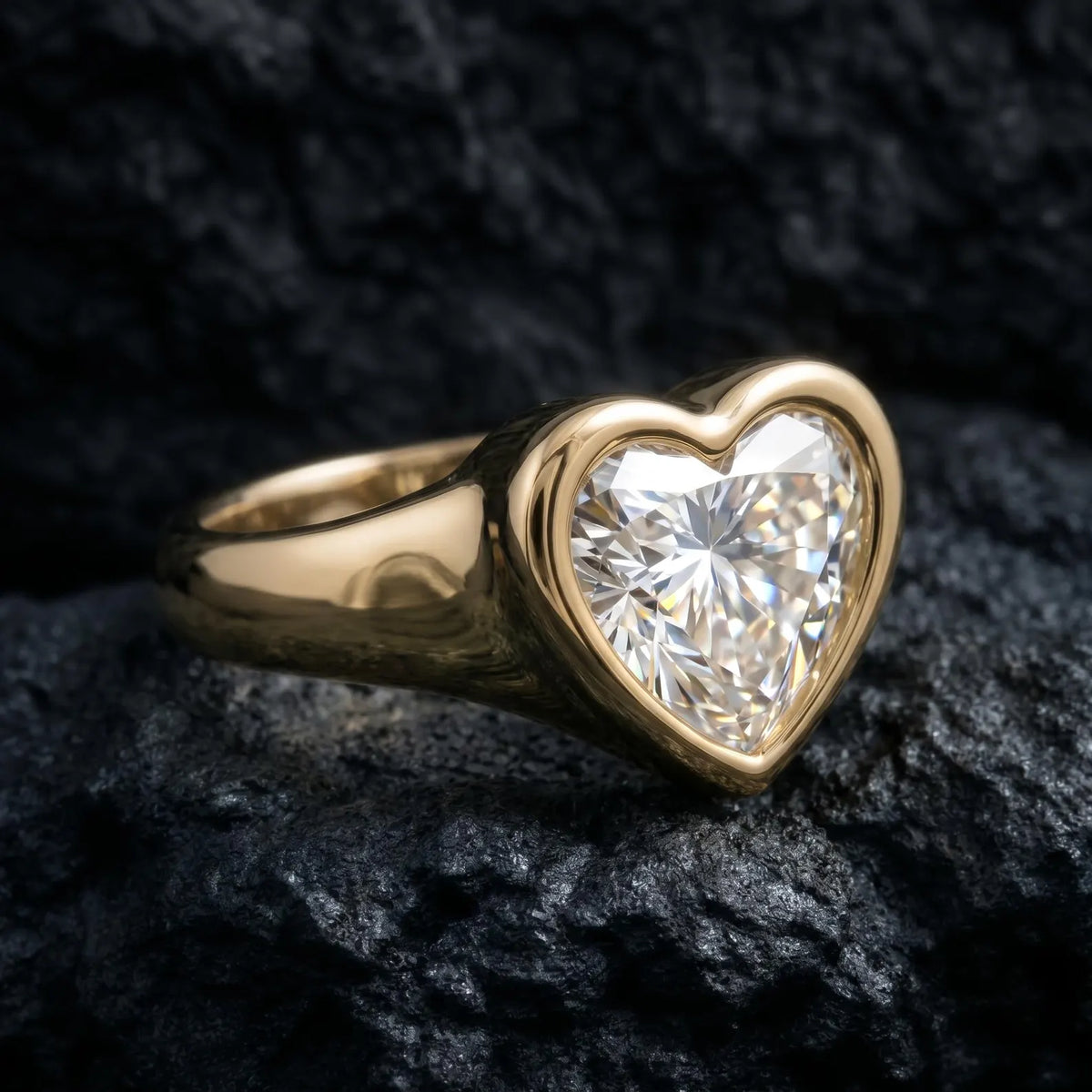3 CT heart lab-grown diamond ring in a smooth yellow gold full bezel signet setting, angled view on dark rock background.
