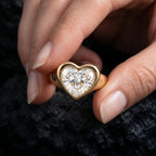 Hand holding a 3 CT heart-shaped lab-grown diamond bezel ring against a textured dark background.