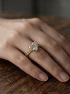 Close-up view of a 2 carat heart-cut lab-grown diamond ring worn on finger against a warm wooden background.