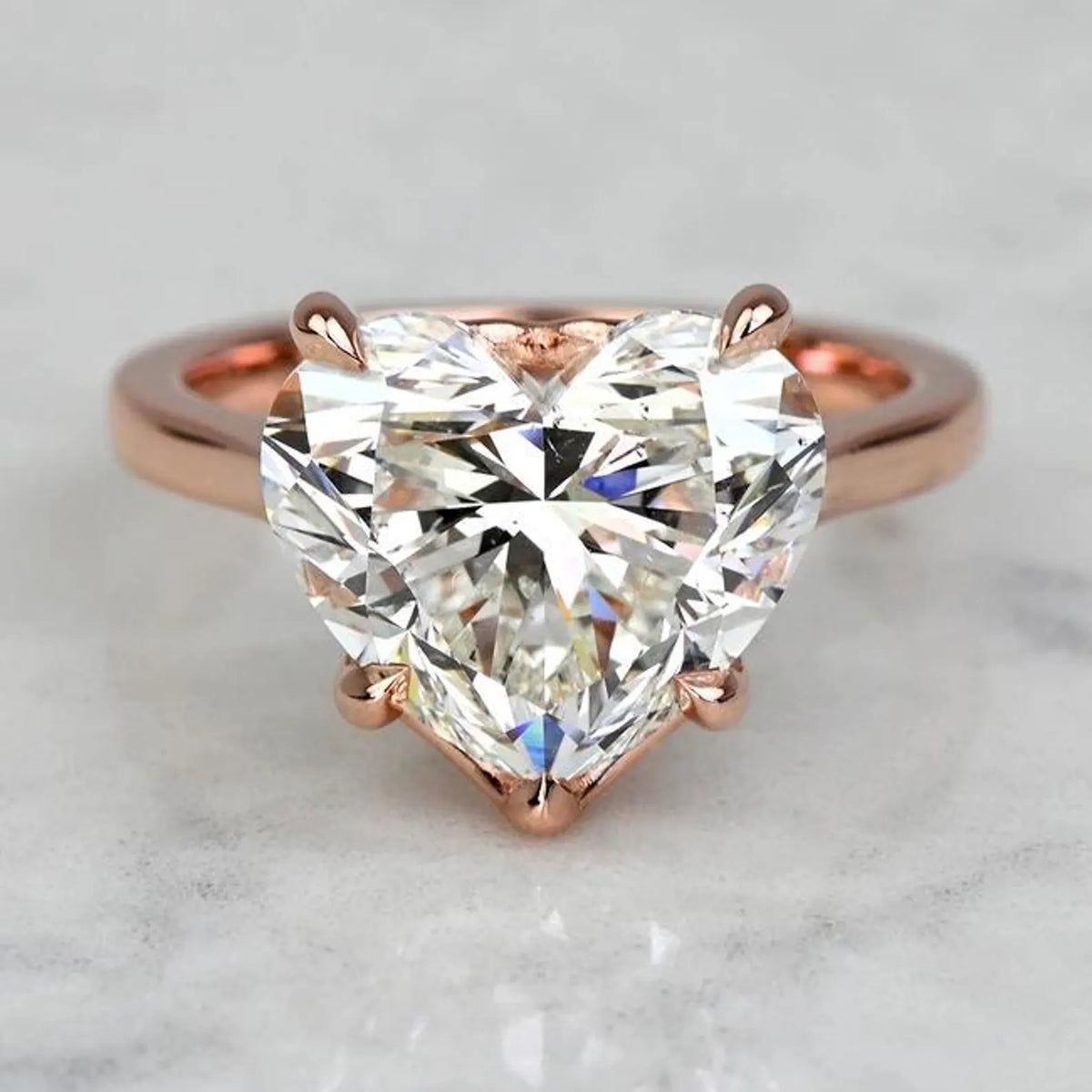 Front top view of a 3 carat heart cut lab-grown diamond solitaire ring set in 14K rose gold prongs.