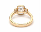 Underneath view of yellow gold bezel frame holding a 4 carat emerald lab-grown diamond and baguette side stones.