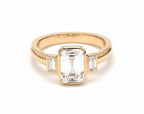 Front view of 4 CT emerald cut lab-grown diamond bezel ring with baguette side stones in 14K yellow gold.