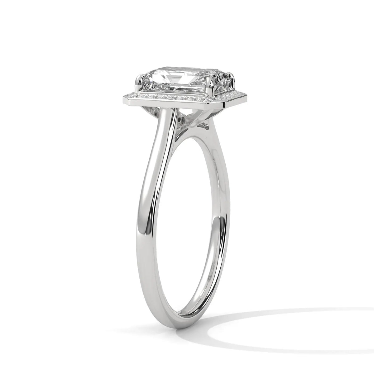 Angled side profile view of a 4 CT emerald cut lab-grown diamond engagement ring with a micro-pave frame halo in 14K white gold.