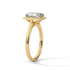 Angled side view of a 4 CT emerald cut lab-grown diamond engagement ring with a pave border in 14K yellow gold.