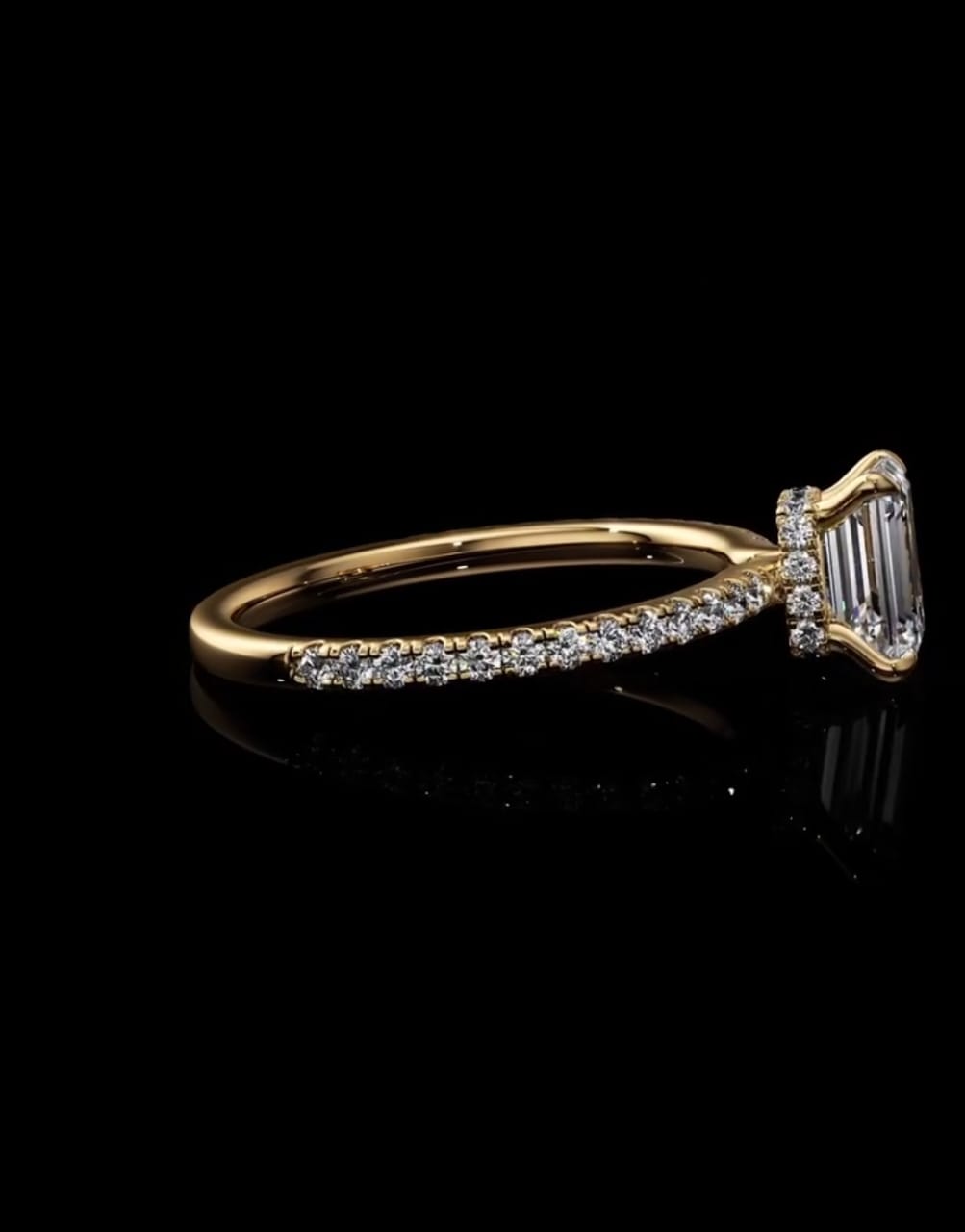 Side profile view of a 2 CT emerald cut lab-grown diamond engagement ring showcasing a diamond-accented hidden halo under-gallery and pavé gold band.