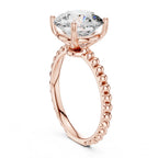 Low vertical angle view showing the basket head and beaded band of a 3 CT round lab diamond ring in rose gold.