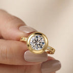 Close-up view of a hand holding a 3 CT round lab grown diamond ring showcasing the intricate milgrain bezel frame and pave shoulder accents.