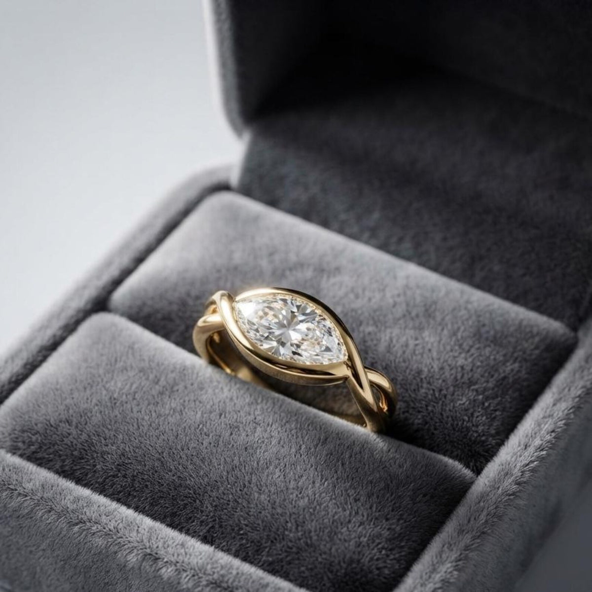 2 CT east-west marquise lab grown diamond ring in a yellow gold bypass bezel setting resting inside a gray velvet ring box.