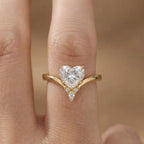 On-finger view of a 2 CT heart cut lab grown diamond engagement ring with a yellow gold chevron band and diamond accent cluster.