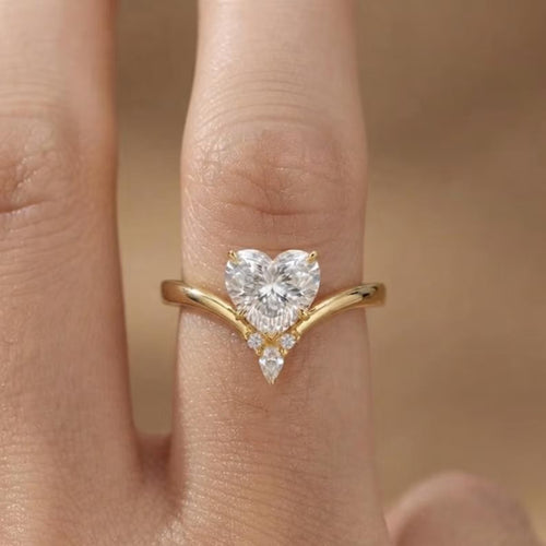On-finger view of a 2 CT heart cut lab grown diamond engagement ring with a yellow gold chevron band and diamond accent cluster.