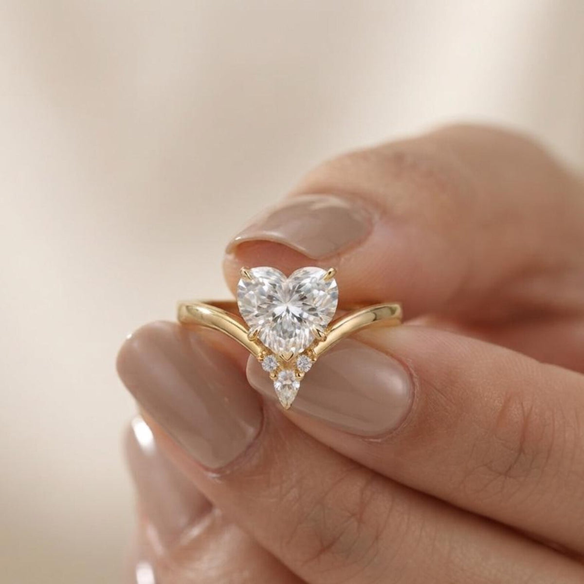 Close-up view of a hand holding a 2 CT heart shaped lab grown diamond ring featuring a curved yellow gold band.