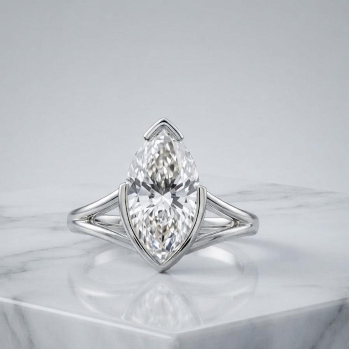 3 CT marquise lab grown diamond engagement ring in platinum with a split shank setting resting on a white marble surface.