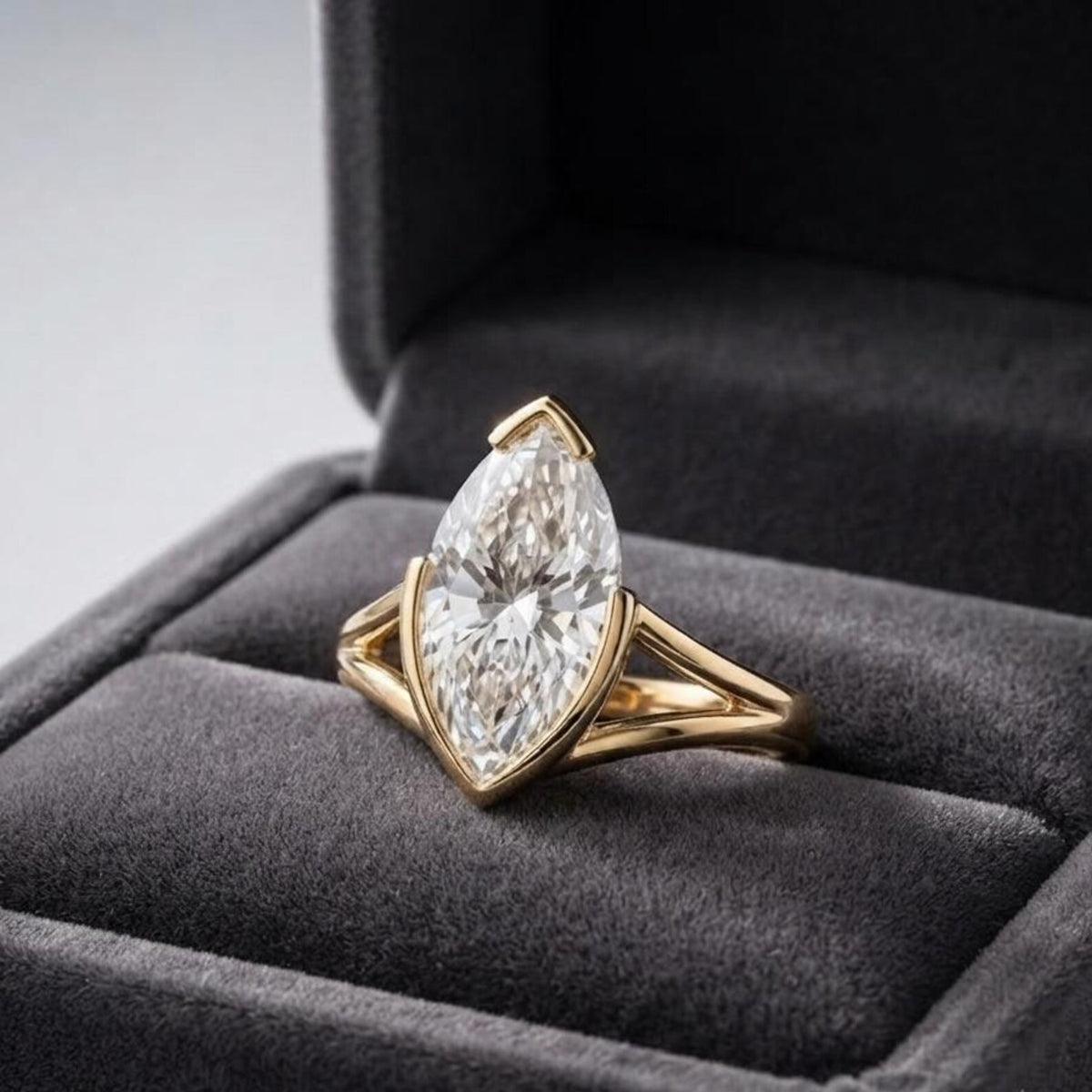 3 carat marquise cut lab diamond ring with a yellow gold split shank band displayed inside a plush gray velvet box.