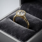 Angled side profile of a 3 carat round lab diamond milgrain bezel solitaire ring displayed in a gray velvet box.