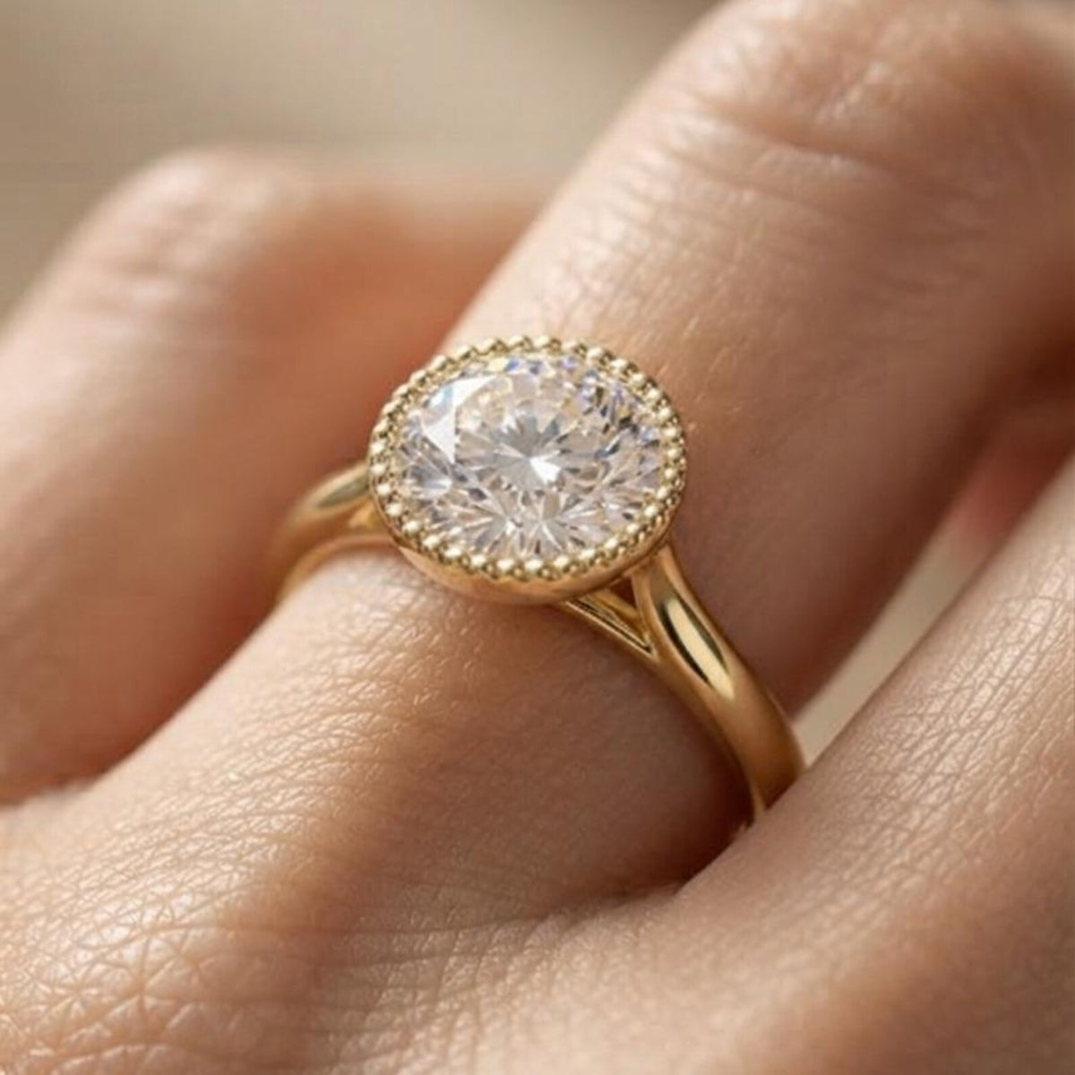 On-finger view of a 3 CT round brilliant lab grown diamond ring with a vintage milgrain bezel rim in yellow gold.