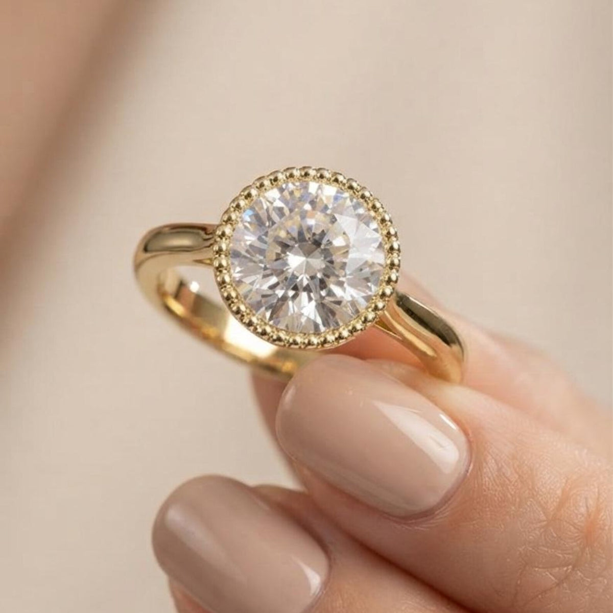 Detailed close-up view of a hand holding a 3 carat round lab diamond solitaire ring showcasing the textured milgrain border.