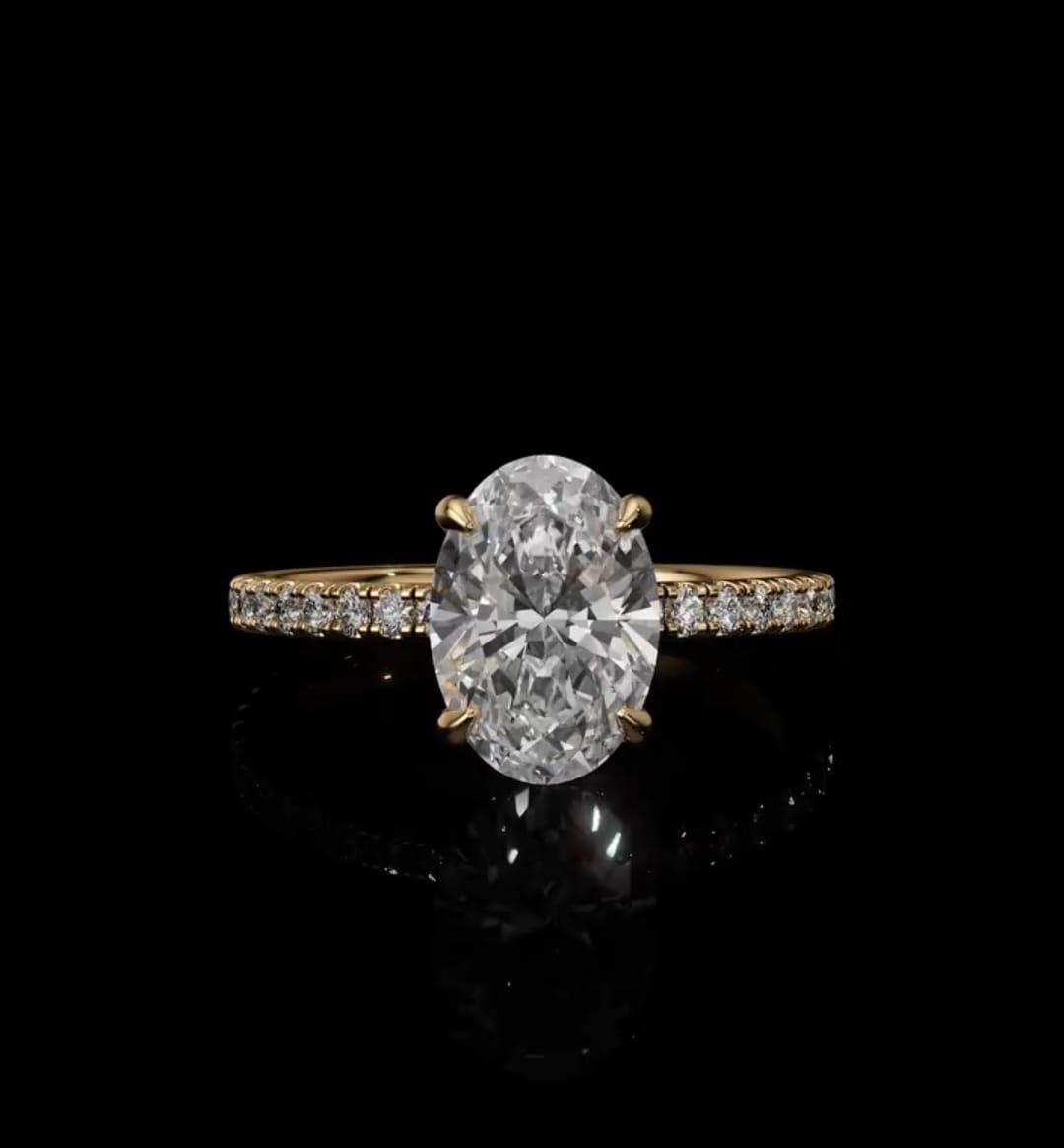 Top view of a 2 CT oval cut lab-grown diamond engagement ring set in four yellow gold prongs on a delicate micro-pavé band.
