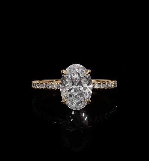 Top view of a 2 CT oval cut lab-grown diamond engagement ring set in four yellow gold prongs on a delicate micro-pavé band.
