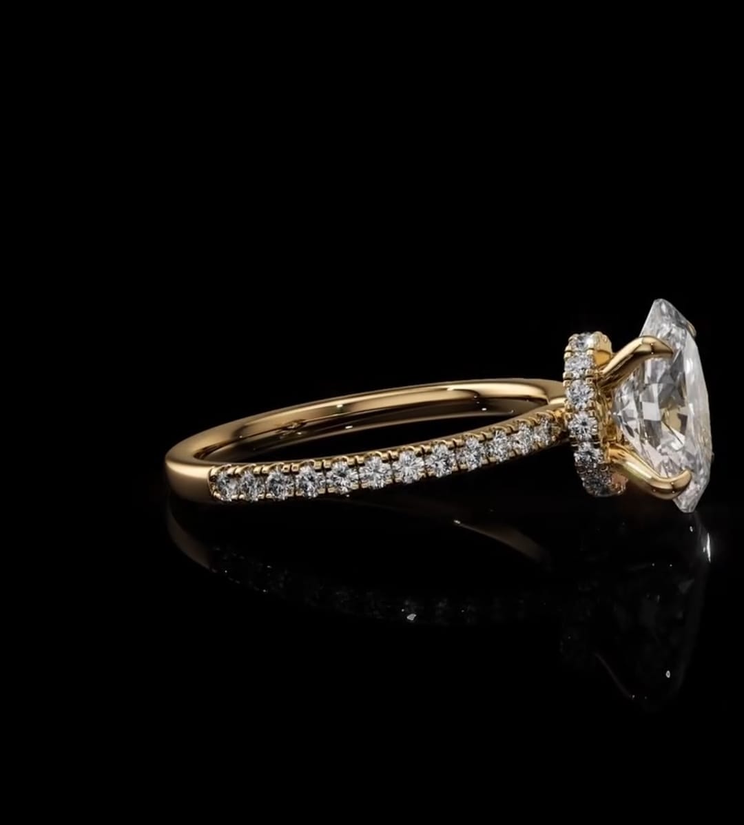 A yellow gold diamond ring with a large marquise-cut center stone and pavé-set diamonds along the band, displayed on a reflective black background.