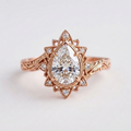 Top-down view of a rose gold 3 CT pear cut lab diamond vintage starburst halo engagement ring.