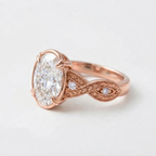 Angled side profile of a rose gold 4 CT oval cut lab grown diamond engagement ring with a leaf-engraved twisted band.