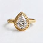 Top-down view of a yellow gold 3 CT pear cut lab grown diamond engagement ring with openwork filigree bezel and floral engraving.