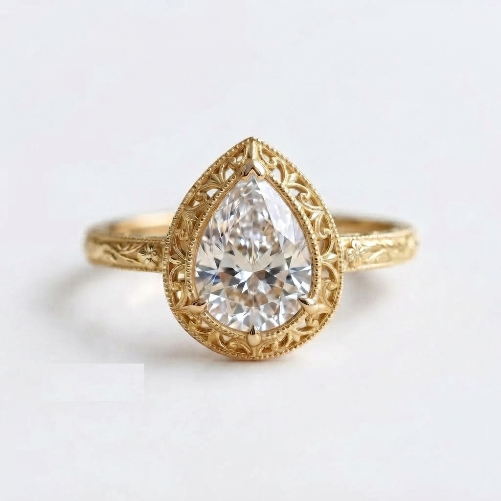 Top-down view of a yellow gold 3 CT pear cut lab grown diamond engagement ring with openwork filigree bezel and floral engraving.