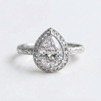 Top-down view of a white gold 3 CT pear cut lab grown diamond ring featuring vintage lace filigree border and carved band.