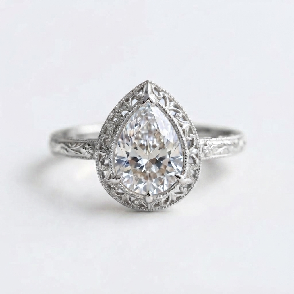 Top-down view of a white gold 3 CT pear cut lab grown diamond ring featuring vintage lace filigree border and carved band.