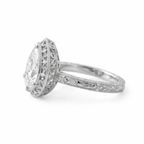 Side profile view of a white gold 3 CT pear diamond ring displaying delicate scroll filigree basket and floral shank.