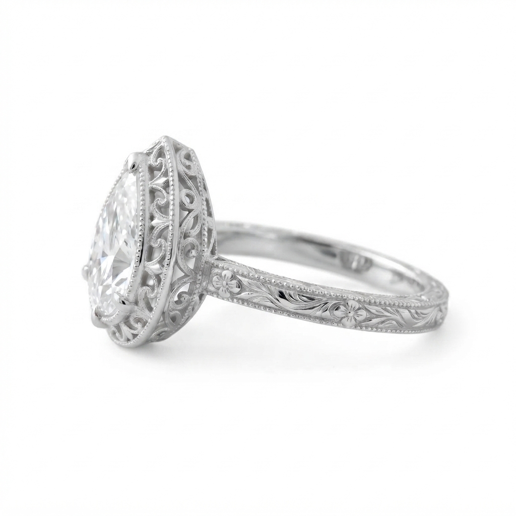 Side profile view of a white gold 3 CT pear diamond ring displaying delicate scroll filigree basket and floral shank.