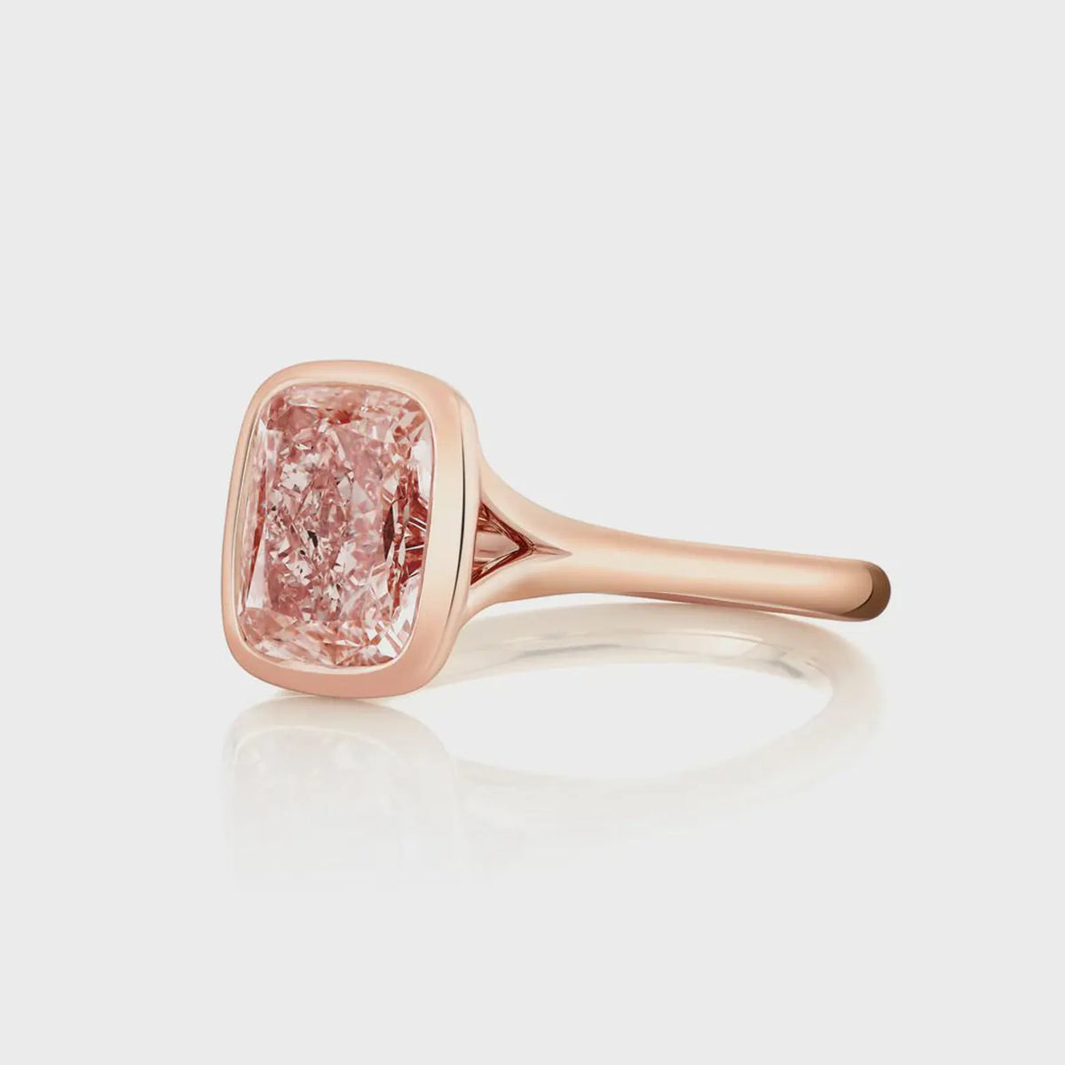 Angled top view of a 2 CT fancy pink cushion cut lab diamond ring in a sleek rose gold bezel setting.